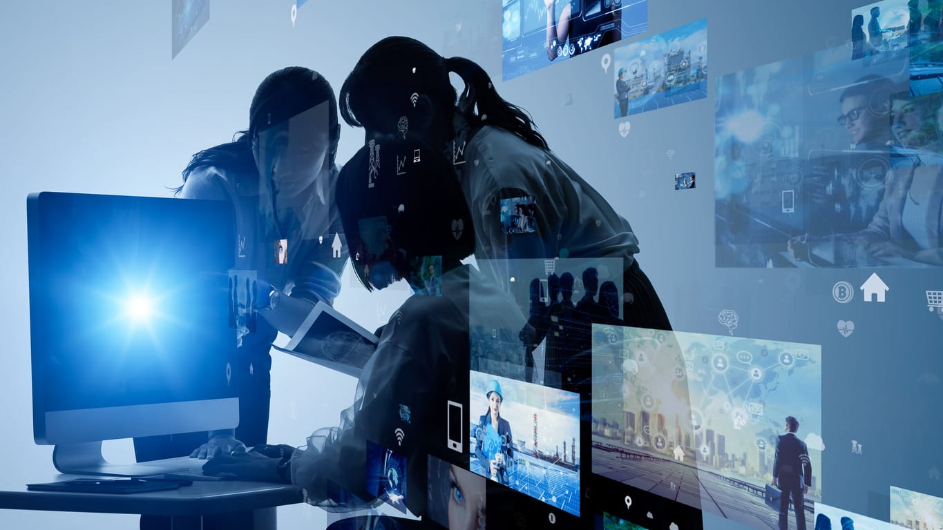 women working in front of computer screen with bright blue light emitting and overlays of multiple images floating through the air while working on a branded video production